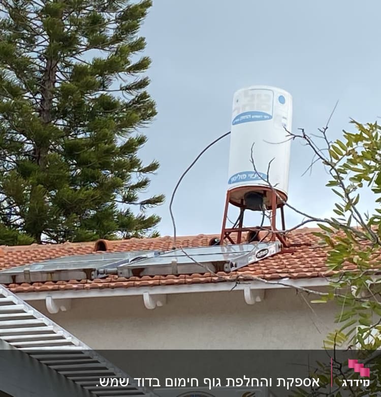 דוד שמש על גג רעפים אדום עם עץ ברקע